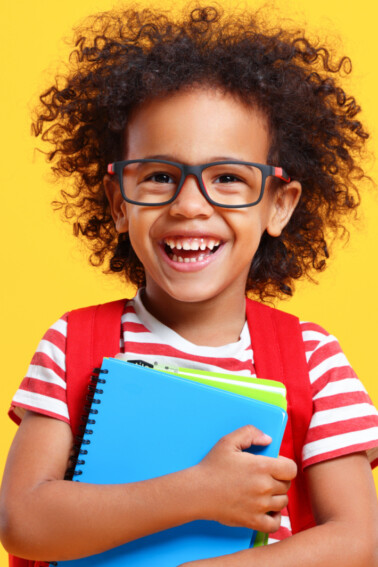 child laughing holding a notebook - back to school jokes for kids