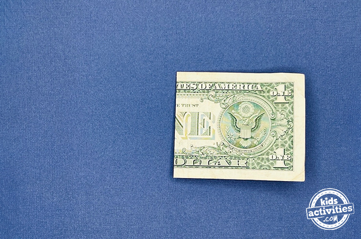 "Dollar bill origami pants - Step 1 - fold it in crosswise. 