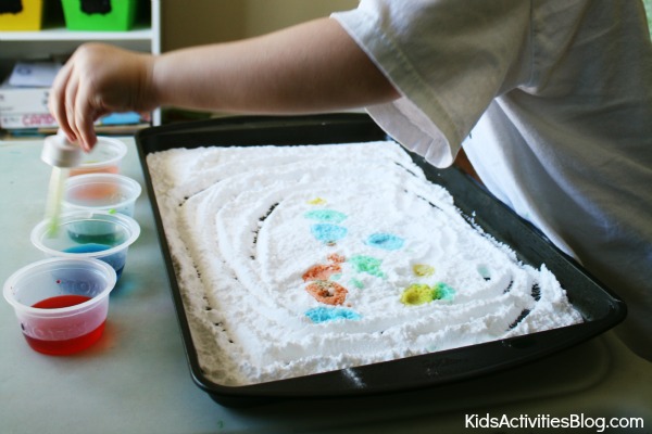 Step 3 - Make Art With Baking Soda And Vinegar - child using an eye dropper to drop vinegar drops onto baking soda that are brightly colored with food coloring - Kids Activities Blog