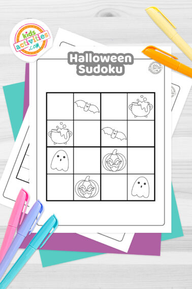 Black and white Halloween sudoku printable with Halloween-themed icons on top such as ghosts, spiders, cauldron, skull, pumpkin, etc; on top of blue-green and purple sheets with assorted crayons on a dark grey background.