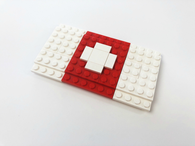 LEGO Fortnite Craft- -step 11- Now we will create the medical cross on the top using the 2X2 white tile and 4 - 1X2 white tiles. Place them in the shape of a cross in the middle of the red 6X6 plate. - kids activities blog