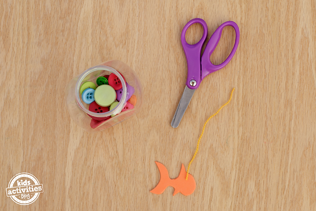 Mini Fishbowl Craft - scissors, jar of buttons, orange fish, and string.