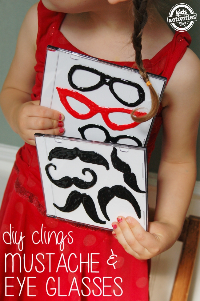 diy mustache and eye glasses clings shown on 2 CD cases being held by a child - Kids Activities Blog