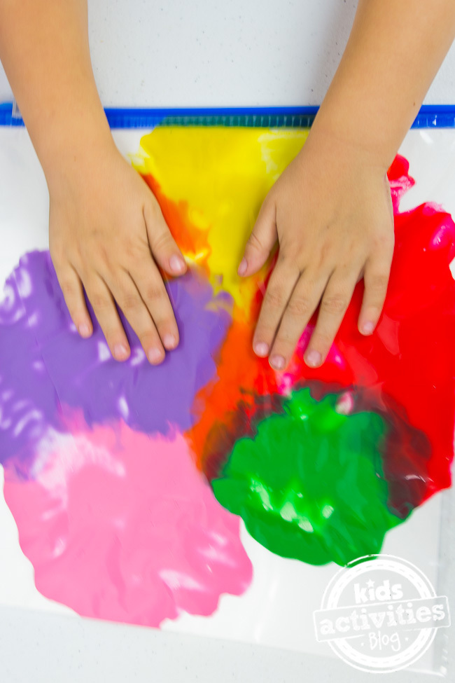 No Mess Finger Painting inside a bag - child's hands pushing and manipulating the finger paint - Kids Activities Blog
