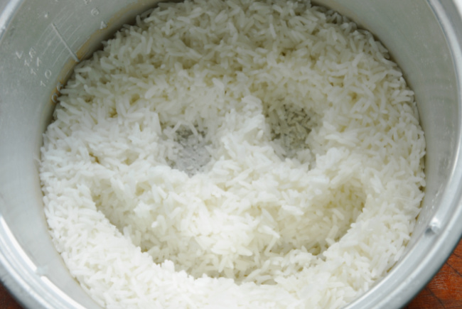 Rice cooking in a rice cooker for fruit sushi recipe - Kids Activities Blog - smiley face in a pan of cooked white rice