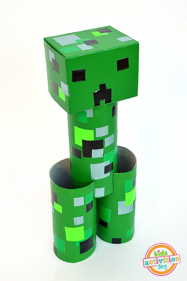 Minecraft Creeper craft made of toilet rolls, paint, paper, and glue shown here on a white background - Kids Activities Blog