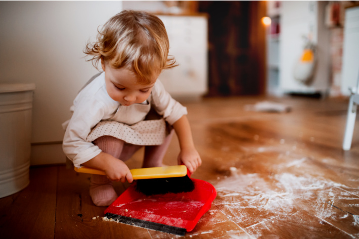 Younger child - toddler using dustpan for chores - Kids Activities Blog