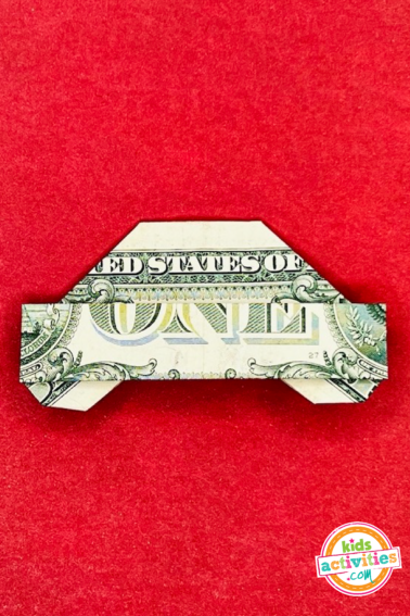 Dollar bill origami car - final result - origami craft on top of a red background. tutorial from Kids activities blog