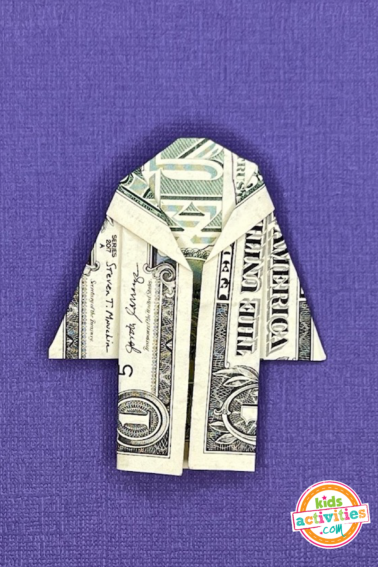 Finished result - dollar bill origami dress on top of a purple background - tutorial from kids activities blog