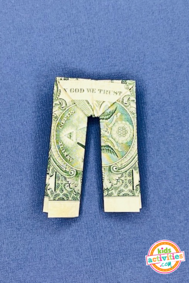 Finished result - dollar bill origami pants on top of a blue background - tutorial from kids activities blog
