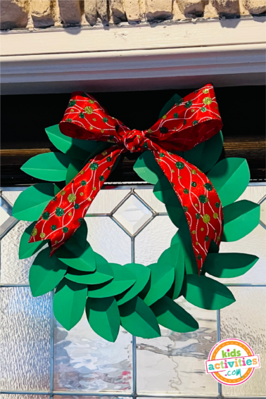 Image shows a finished paper wreath craft hanging from a door frame.